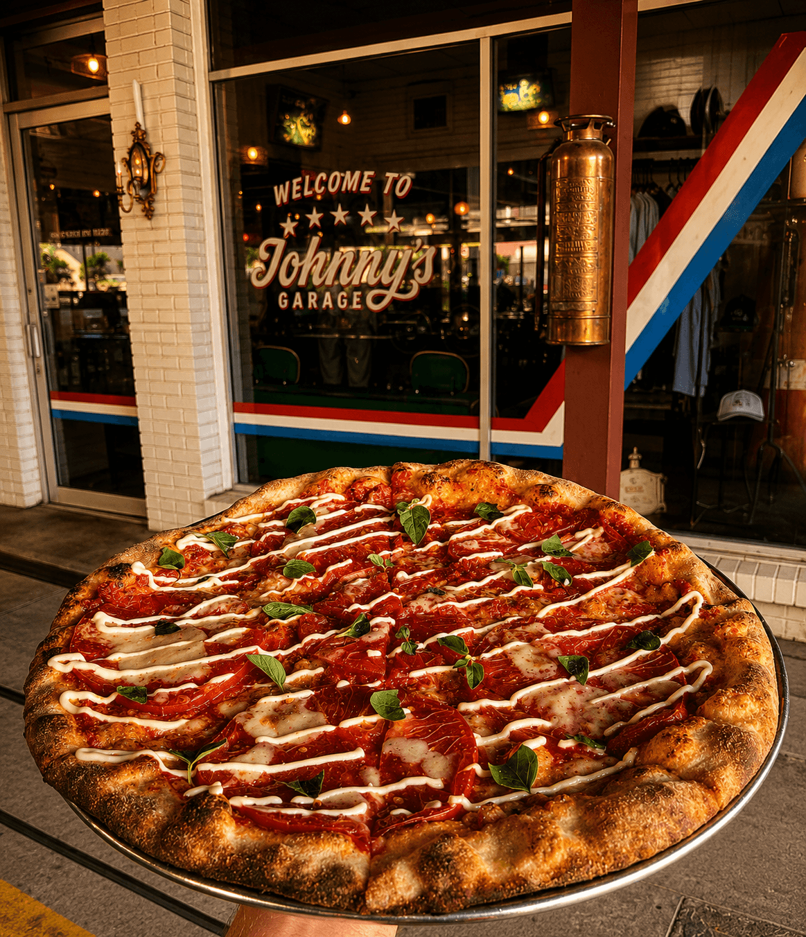 Fresh pizza held in front of the Welcome to Johnny's Garage entrance